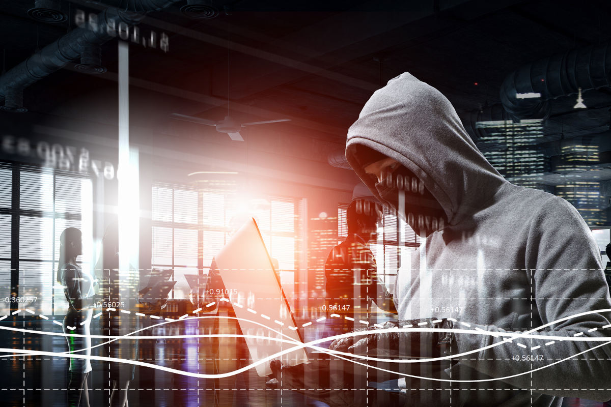 Cyber criminal in gray hoodie using laptop